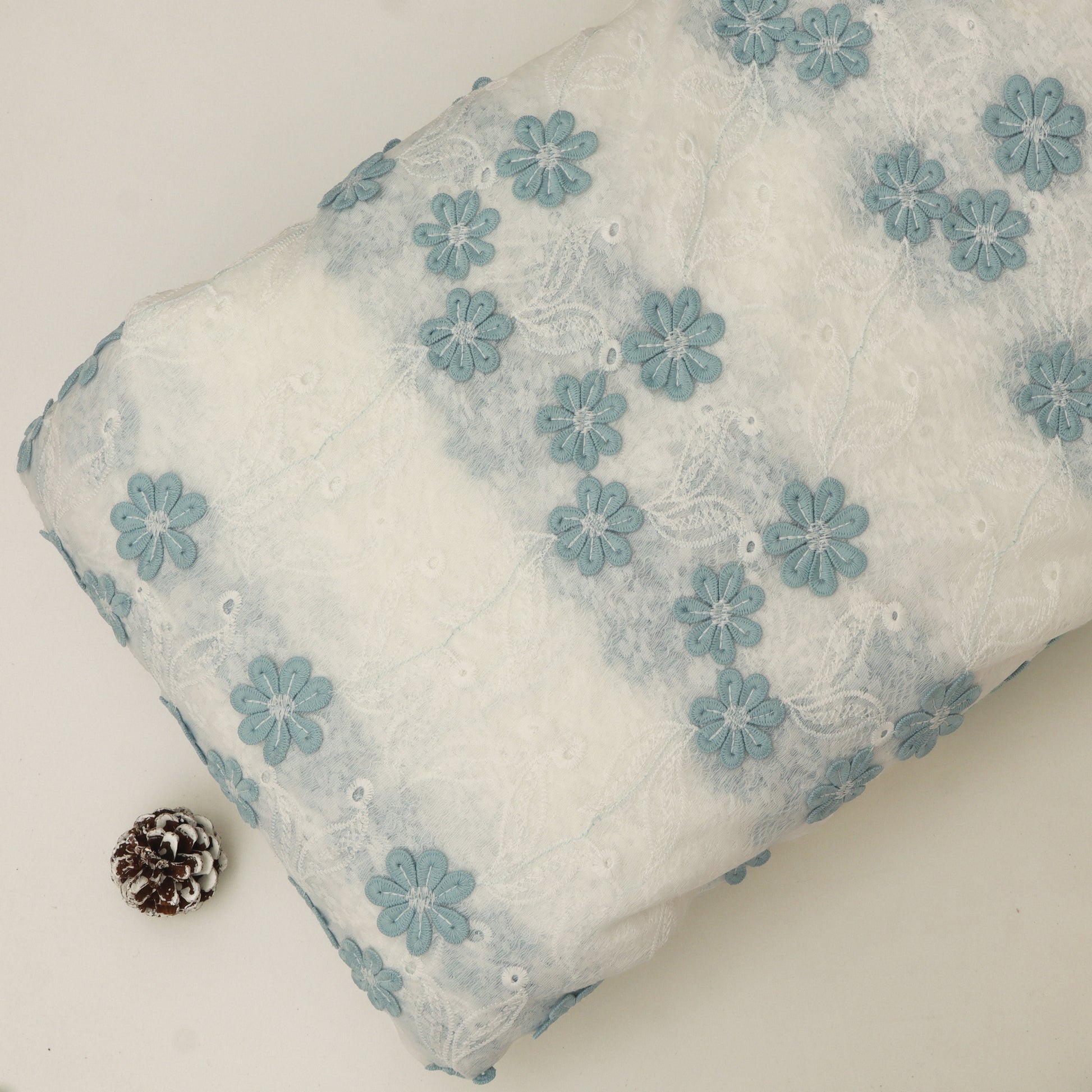 White pillow with blue floral embroidery on a white background