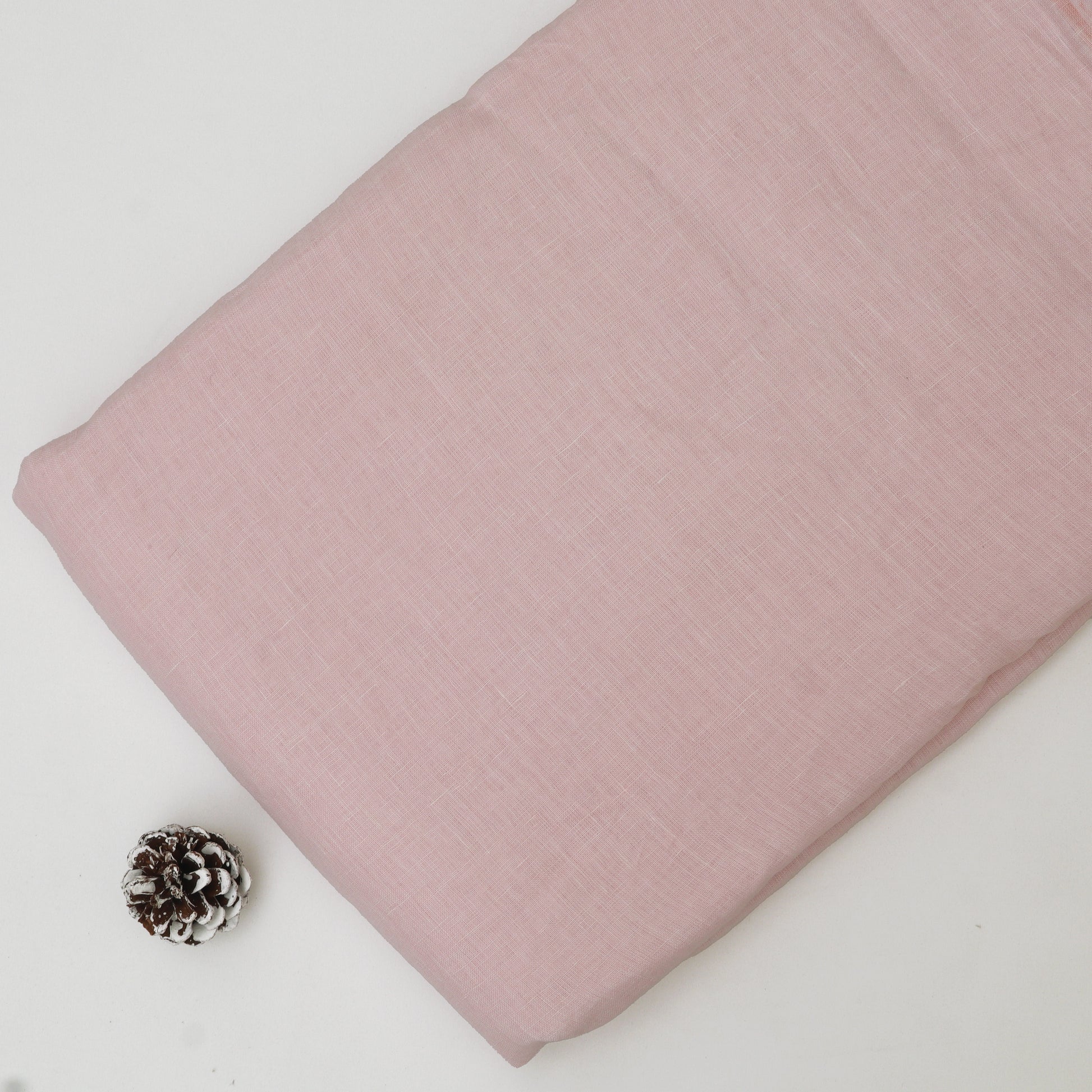 Pink fabric with a pine cone on a white background