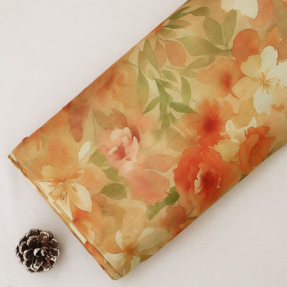 A folded piece of fabric with a watercolor floral print in shades of orange, peach, cream, and green, displayed on a light off-white background next to a small pinecone.