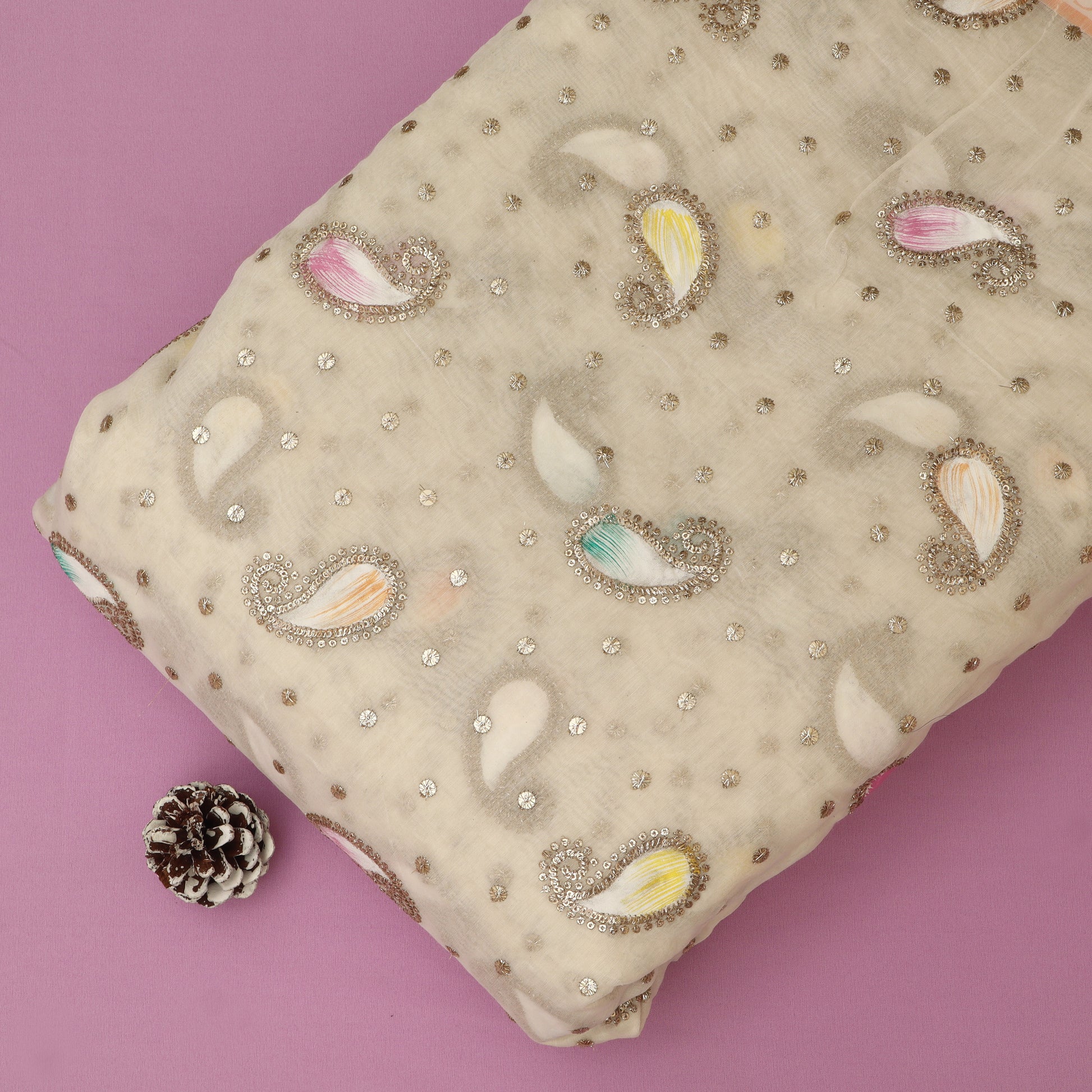 Decorative fabric with paisley patterns and embellishments on a pink background
