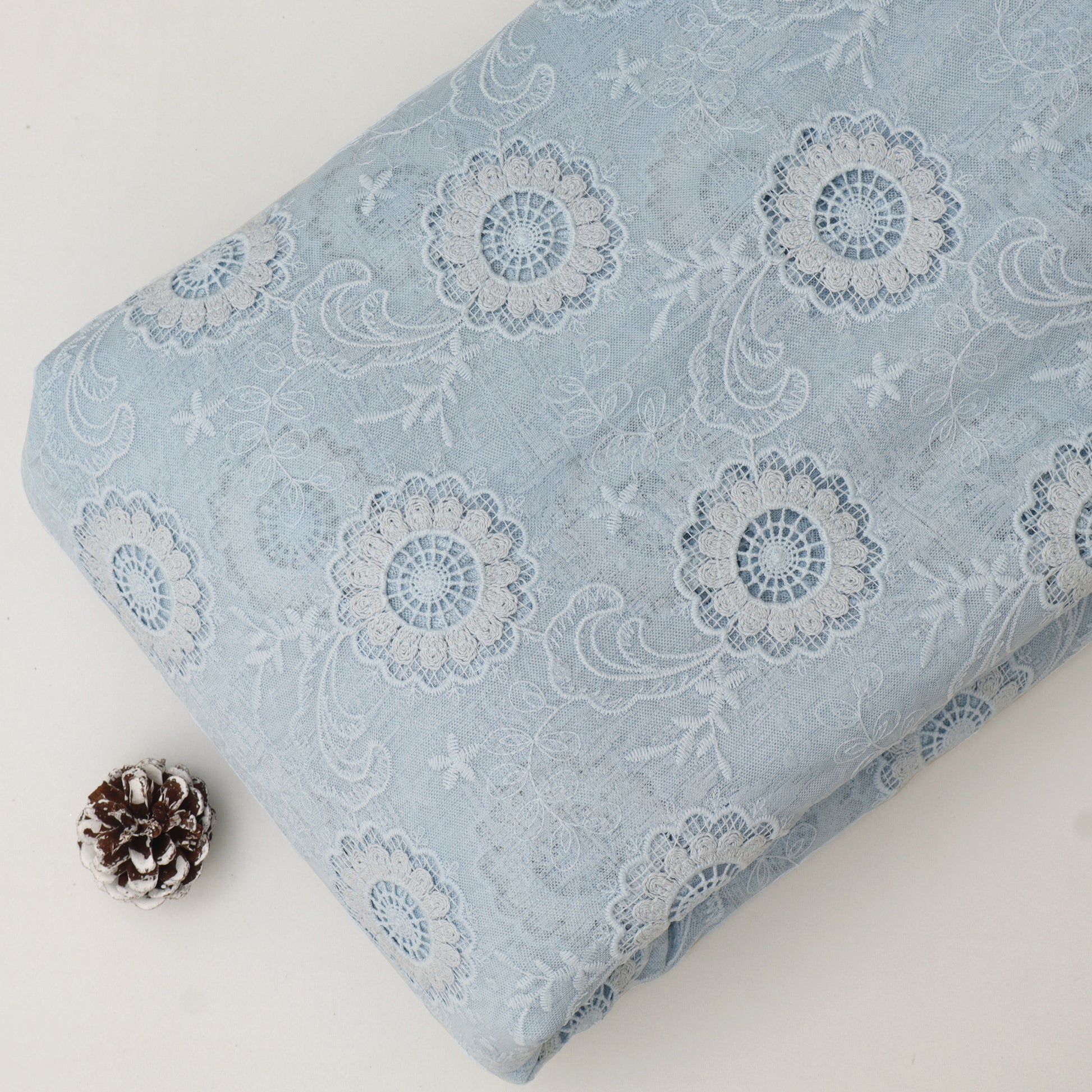 Floral patterned fabric on a white background with a pine cone.