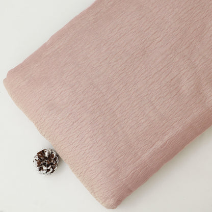 Pink textured fabric with a pine cone on a white background