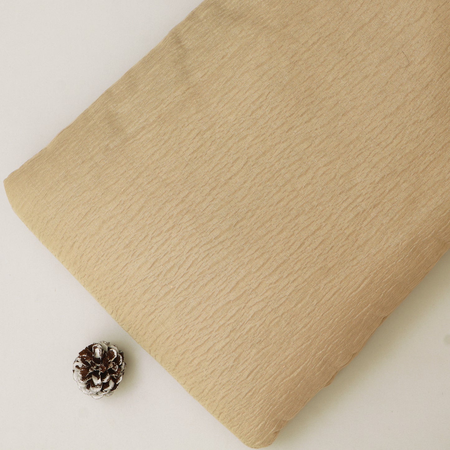 Beige fabric with a pine cone on a light background