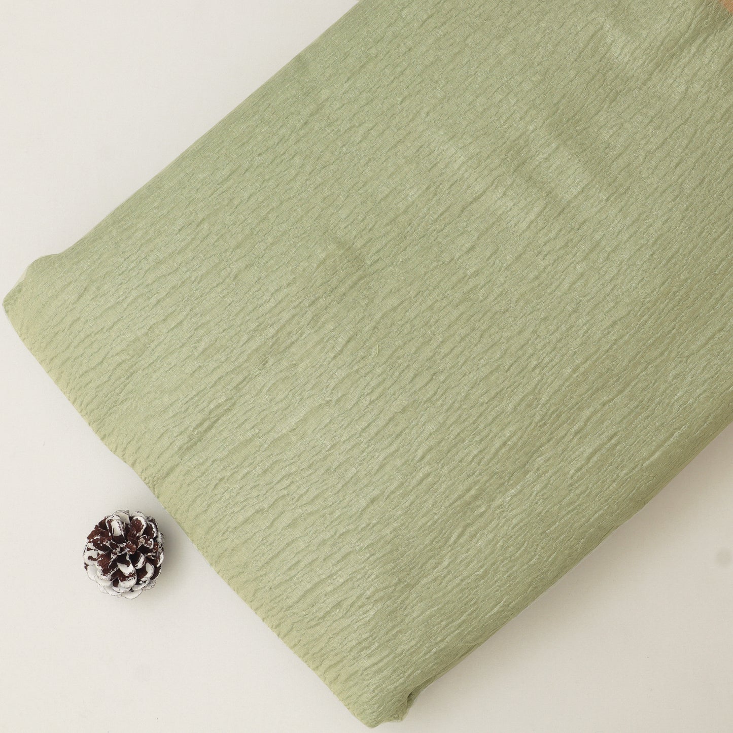 Folded green fabric on a white background with a pine cone.