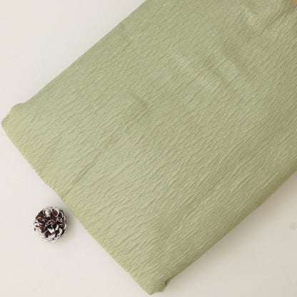 Folded green fabric on a white background with a pine cone.