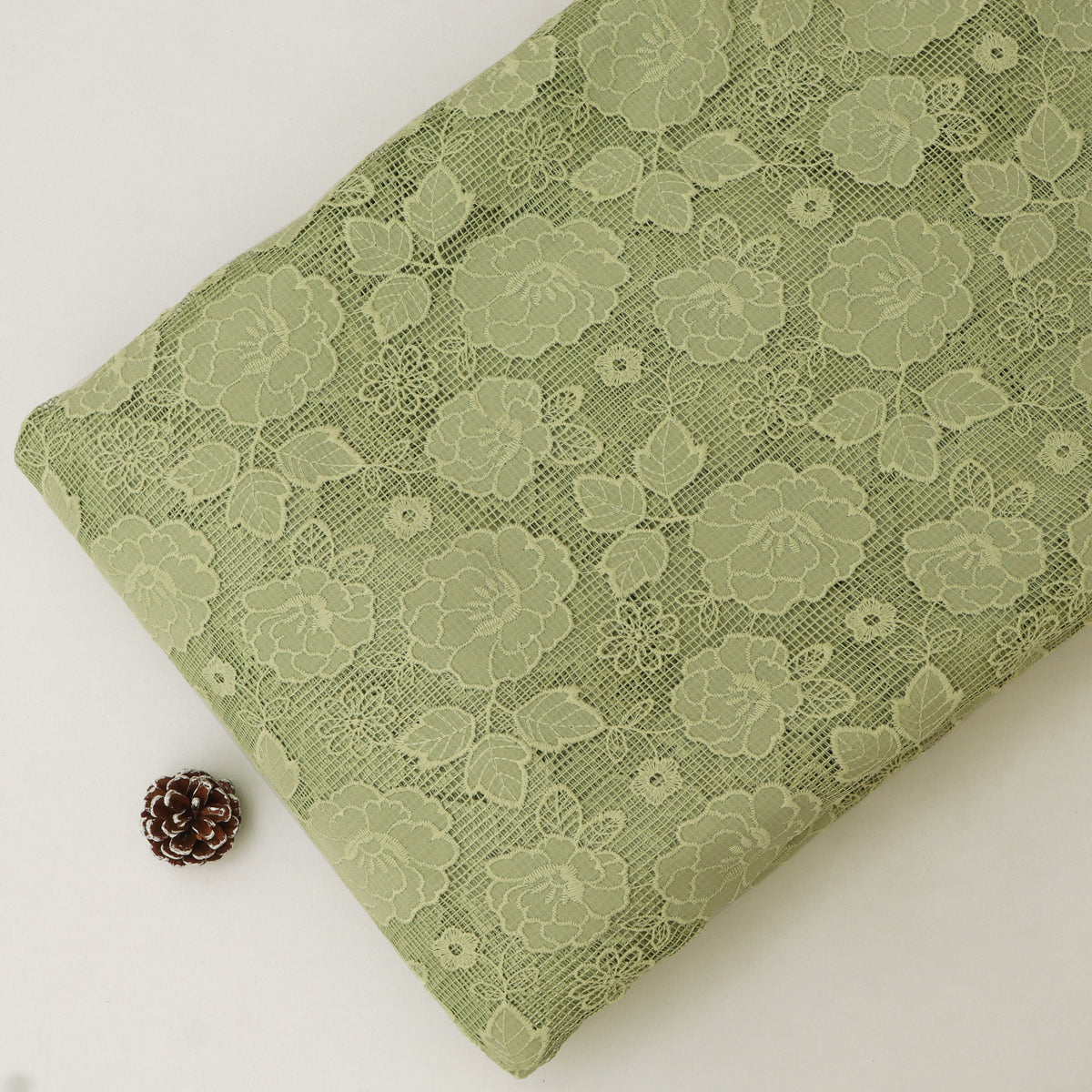 Green lace fabric with floral patterns on a white background
