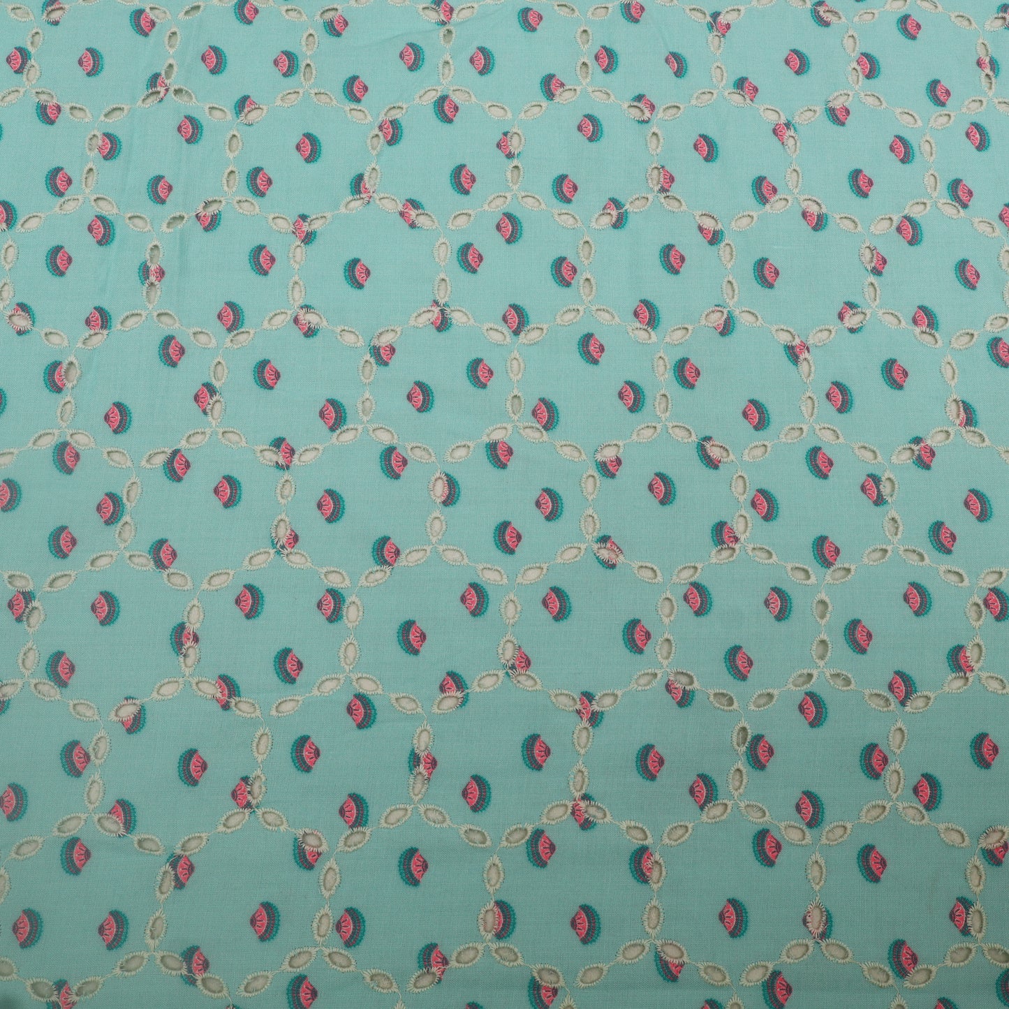 Patterned fabric with small red and green shapes on a teal background