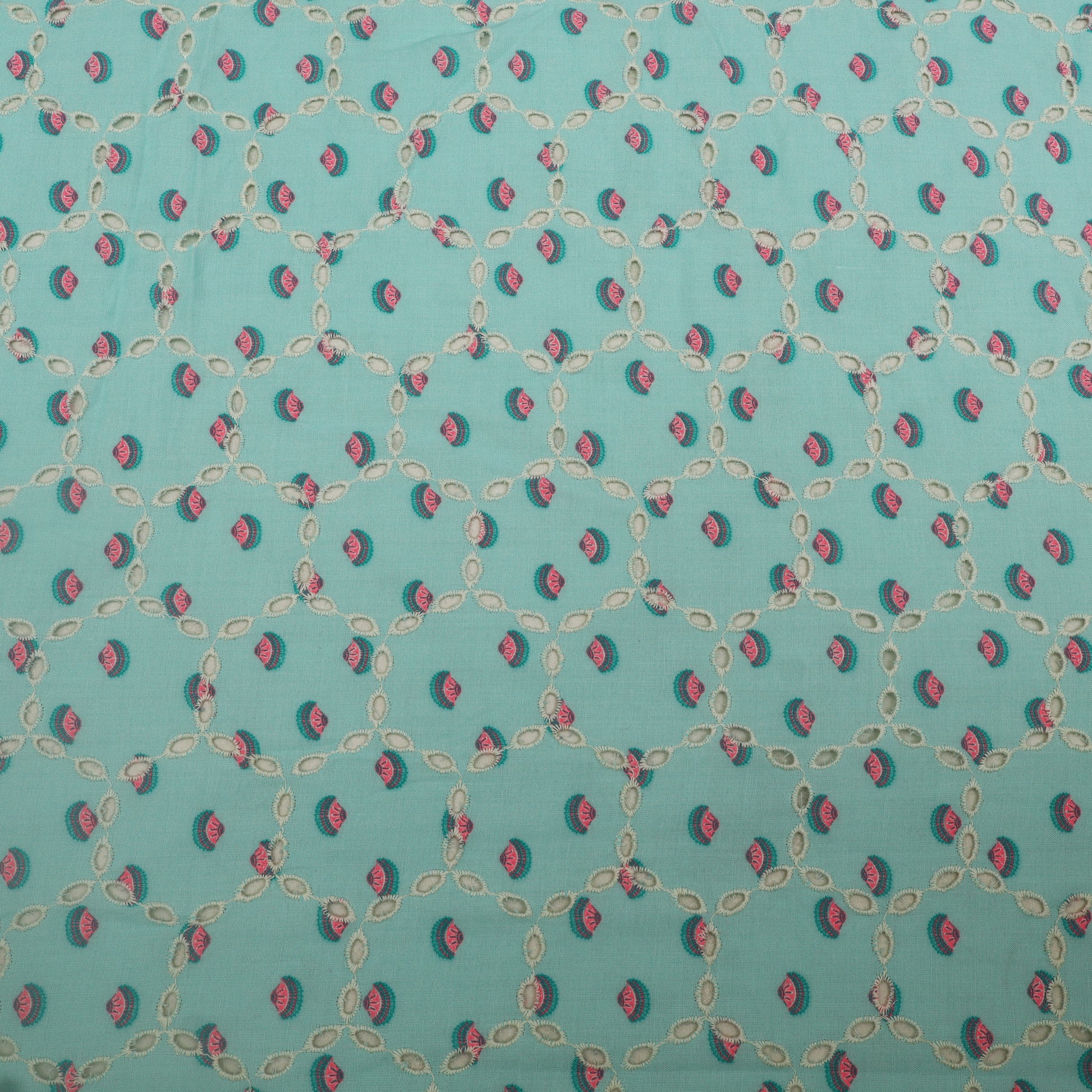 Patterned fabric with small red and green shapes on a teal background