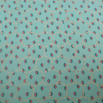 Patterned fabric with small red and green shapes on a teal background