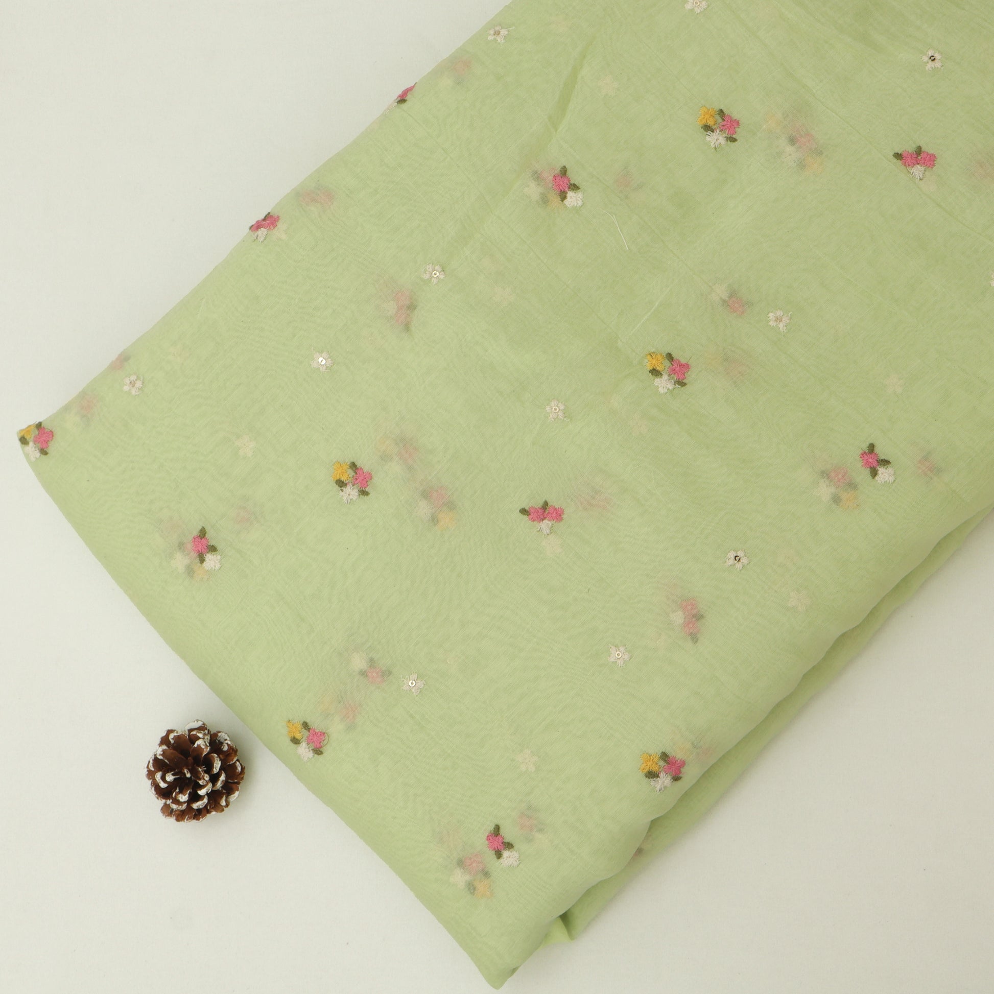 Green fabric with small floral patterns on a light background