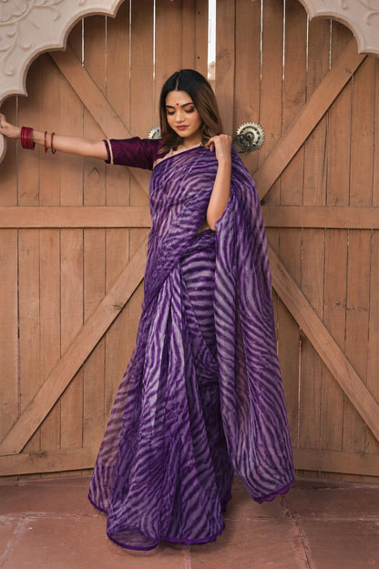 Woman wearing a purple saree with a zebra pattern against a wooden door background