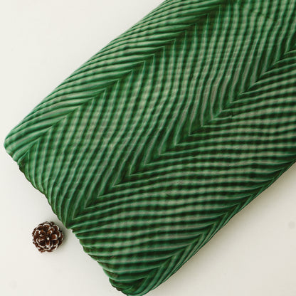 Green textured pillow with a pine cone on a white background