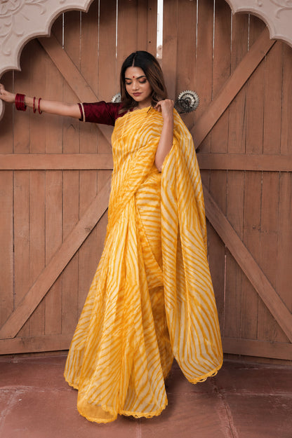 Woman in a yellow saree standing in front of a wooden door