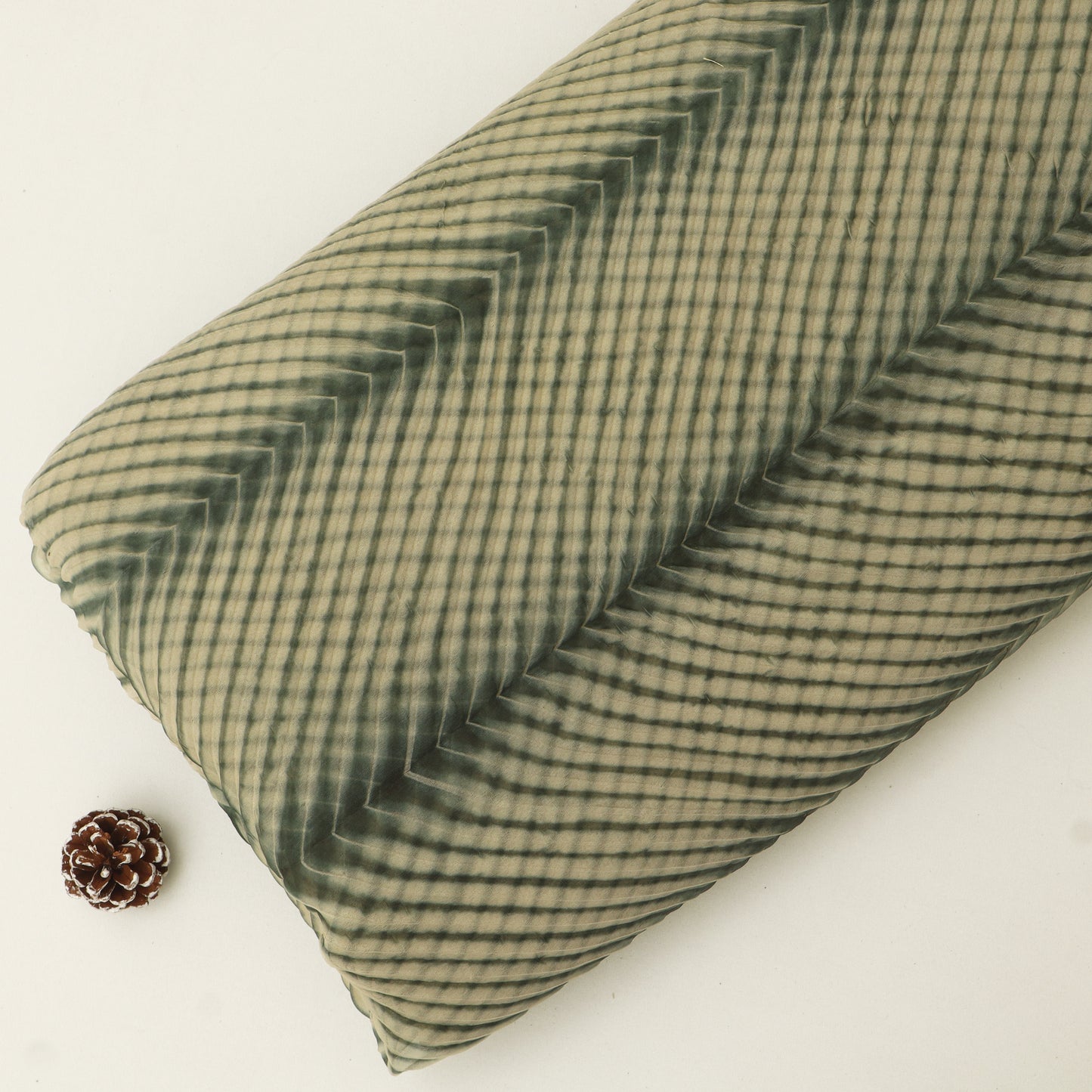 Green checkered fabric roll on a white background with a pine cone.