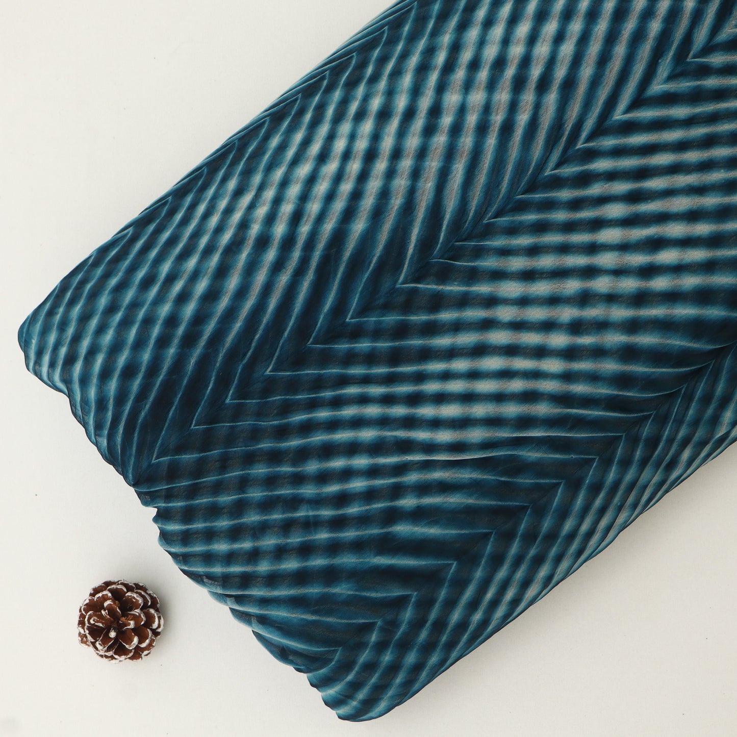 Teal striped fabric with a pine cone on a white background