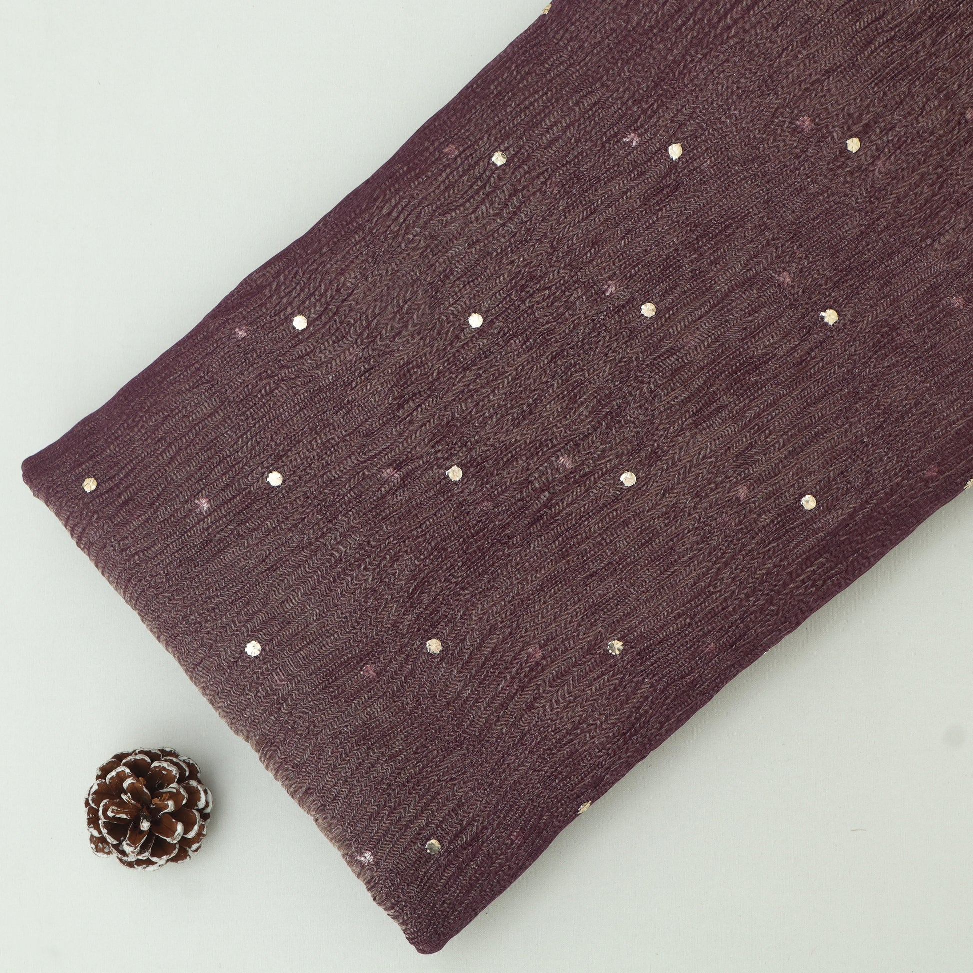 Dark purple fabric with gold studs on a light gray background
