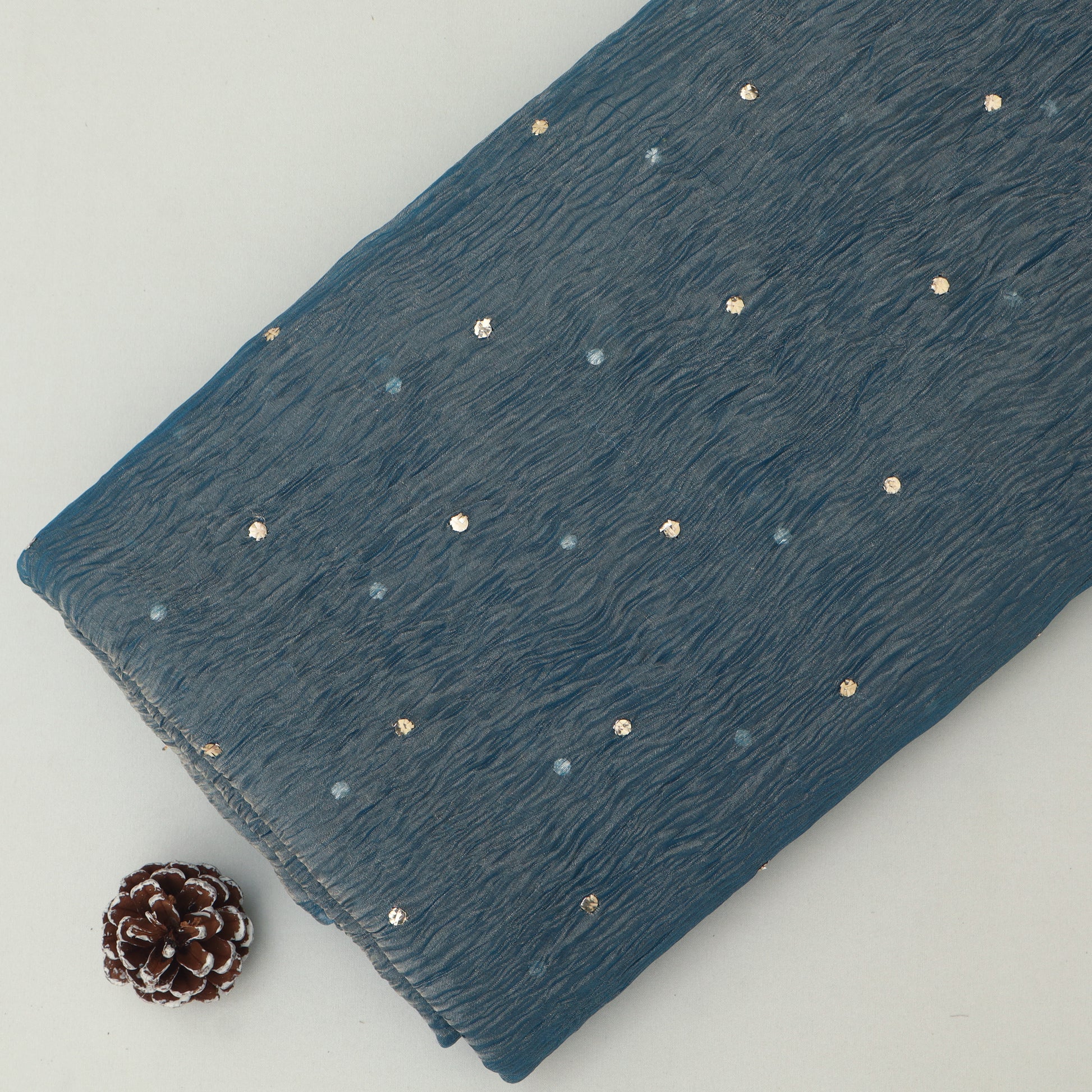 Blue fabric with gold studs on a white background