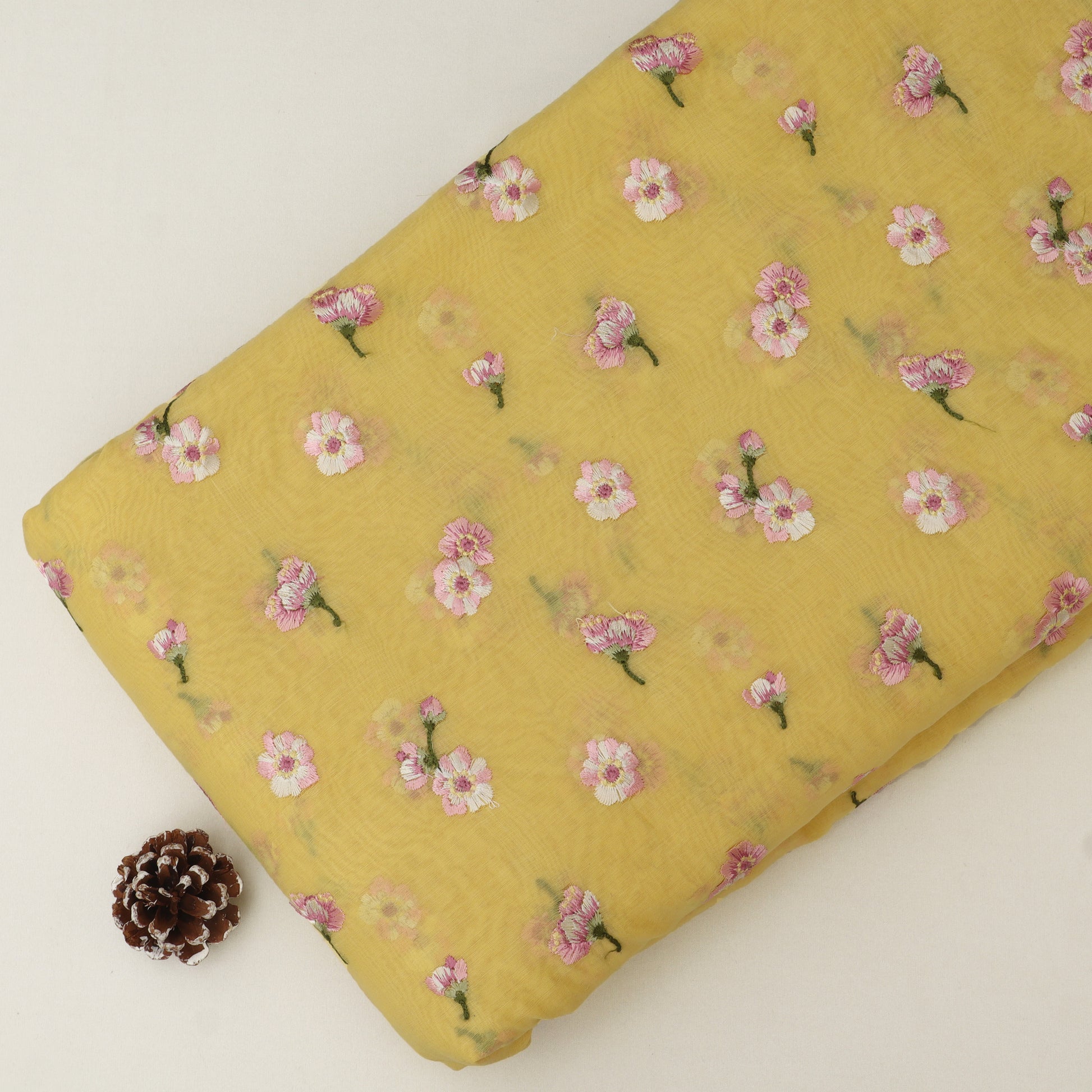 Yellow fabric with pink floral pattern on a white background
