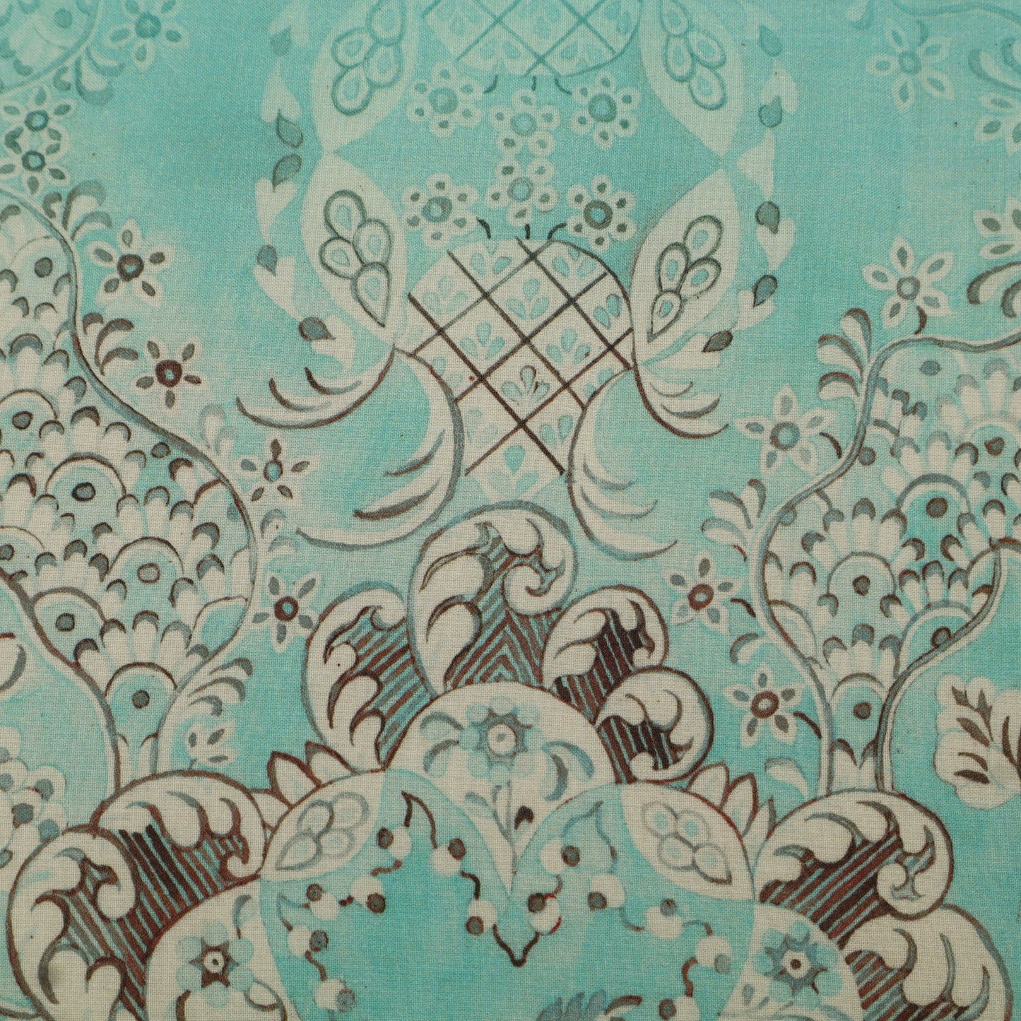 Close-up of a decorative fabric pattern with intricate designs on a teal background