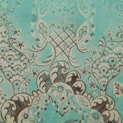 Close-up of a decorative fabric pattern with intricate designs on a teal background