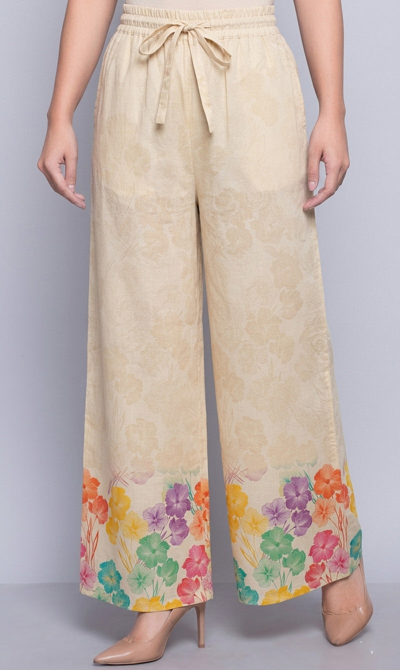 Beige pants with colorful floral pattern at the bottom on a gray background