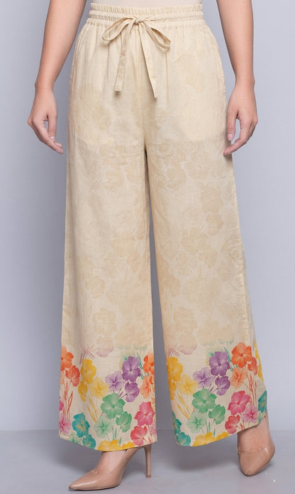 Beige pants with colorful floral pattern at the bottom on a gray background