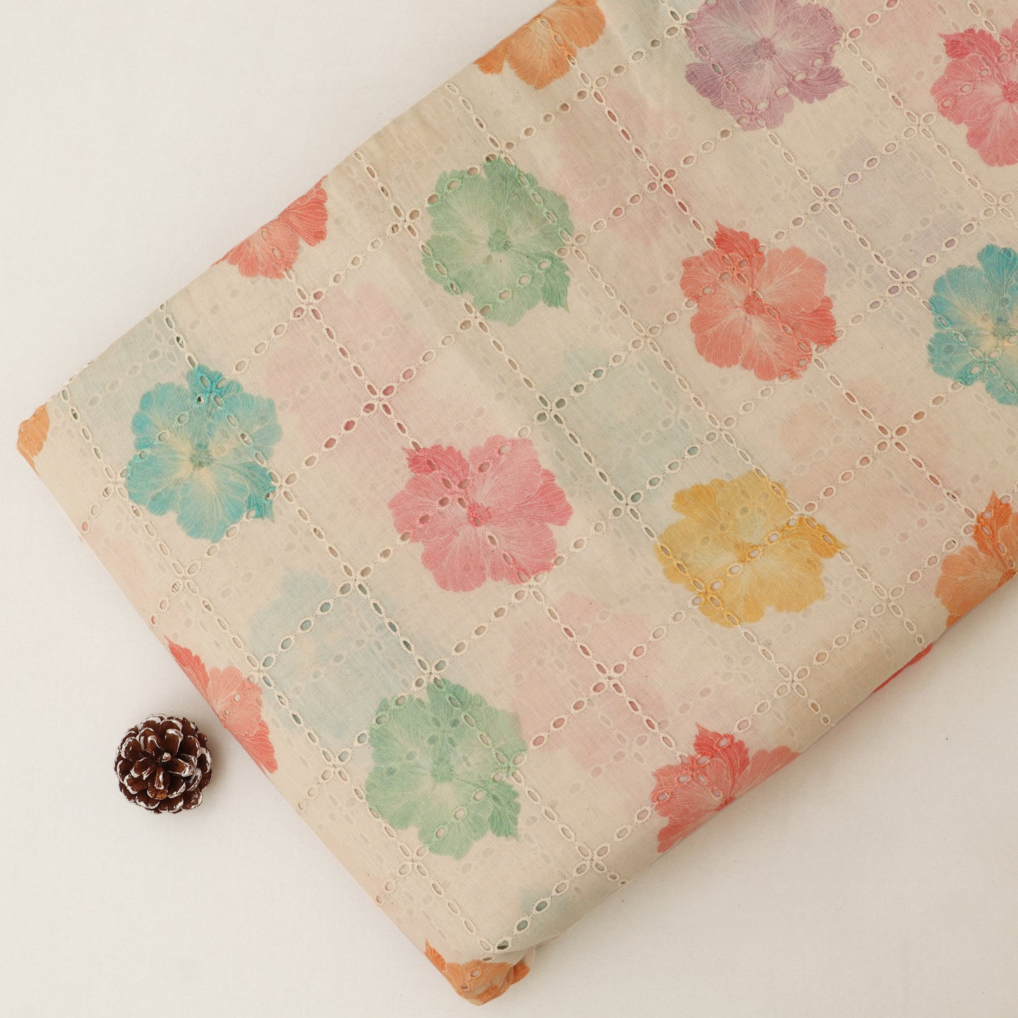 Floral-patterned fabric with a pine cone on a white background
