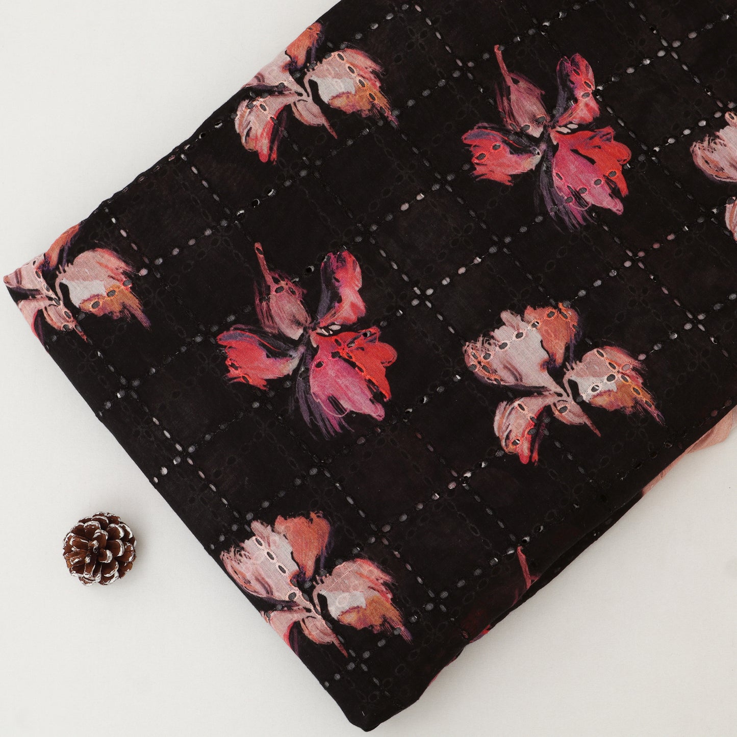 Floral-patterned fabric on a white background with a pine cone