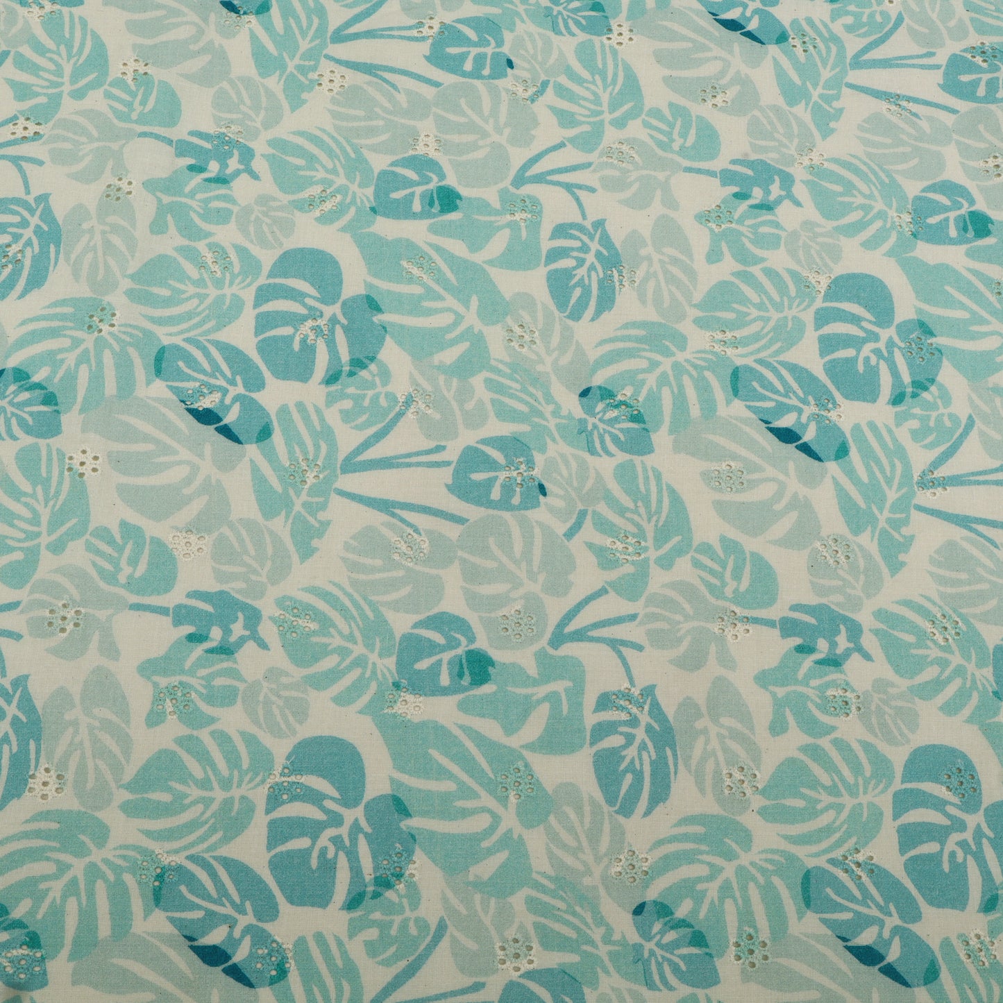 Patterned fabric with blue and green leaves on a light background