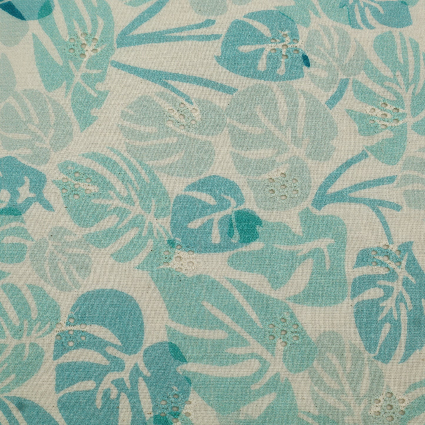 Patterned fabric with blue and green leaves on a beige background