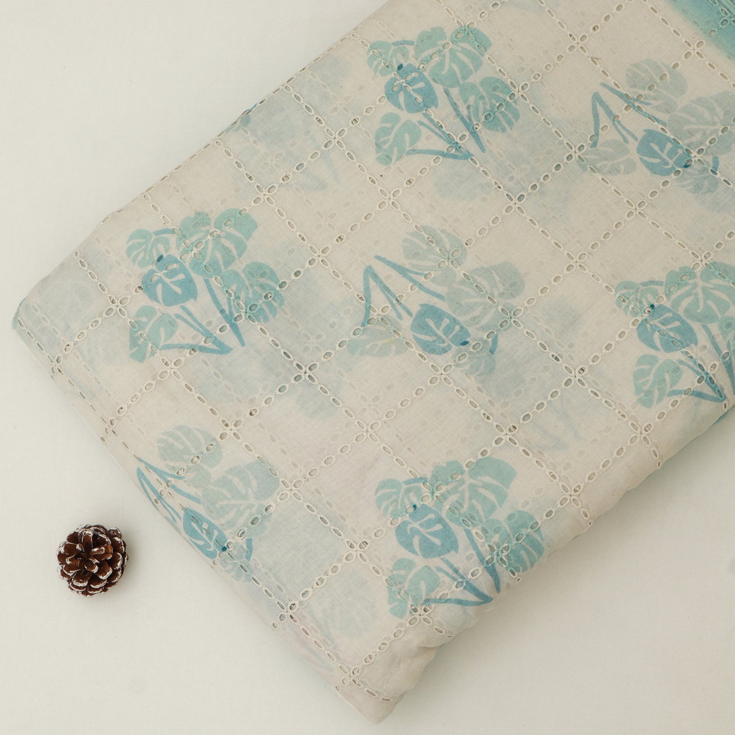 Floral-patterned fabric with a pine cone on a light background