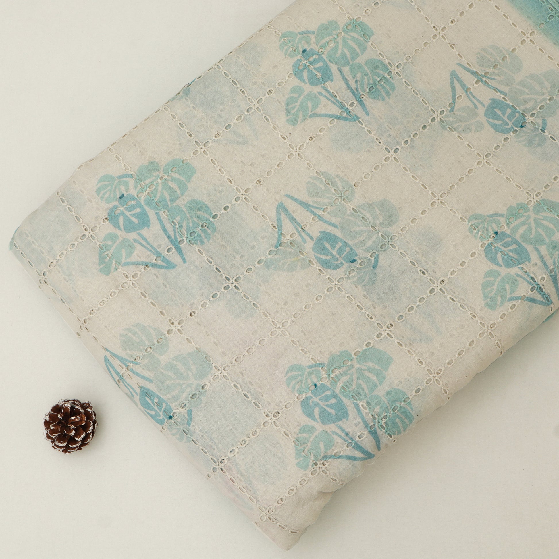 Floral-patterned fabric with a pine cone on a light background