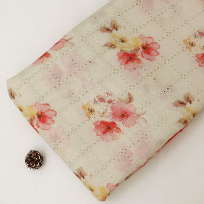 Floral-patterned quilt on a white surface with a pine cone.