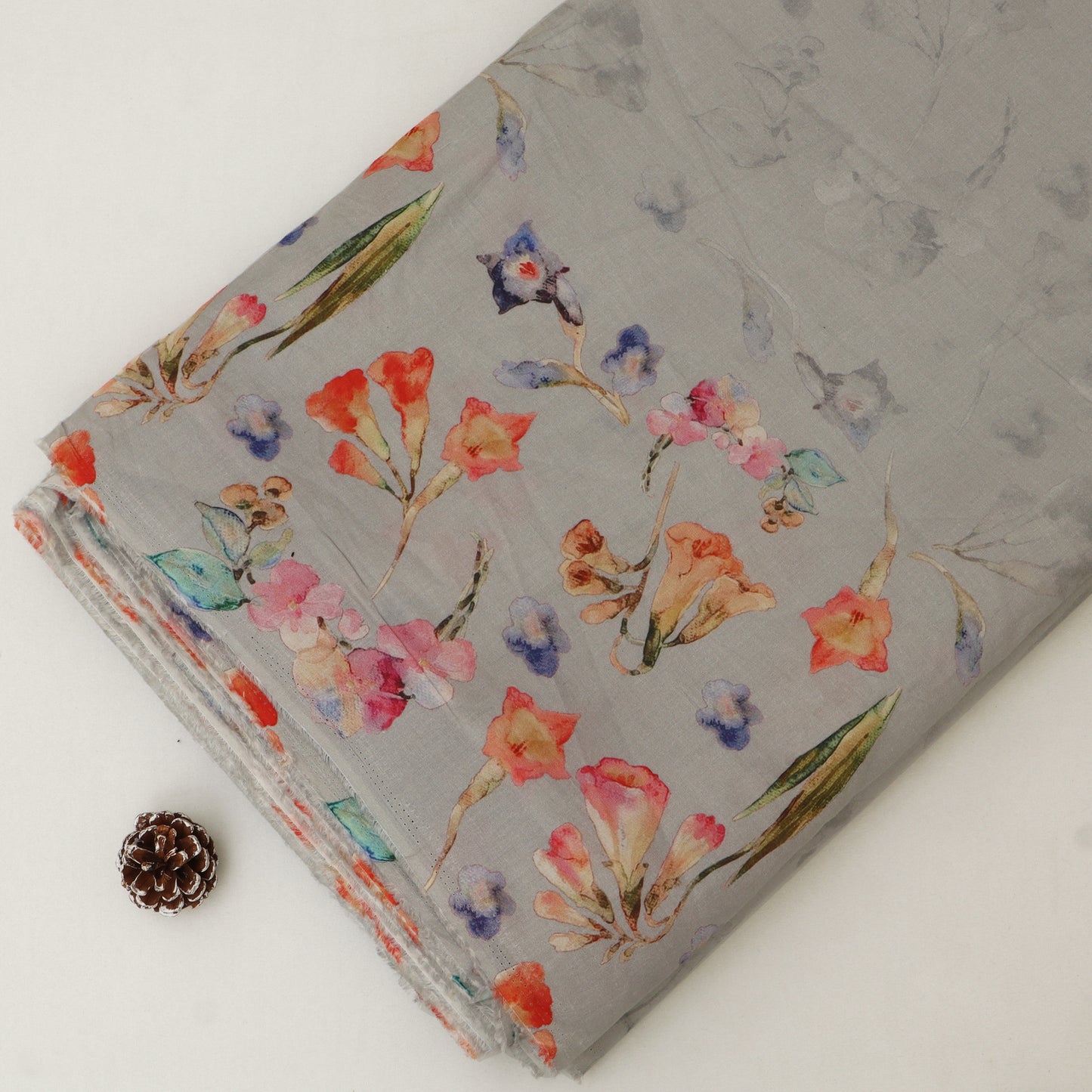 Floral-patterned fabric on a gray background with a pine cone