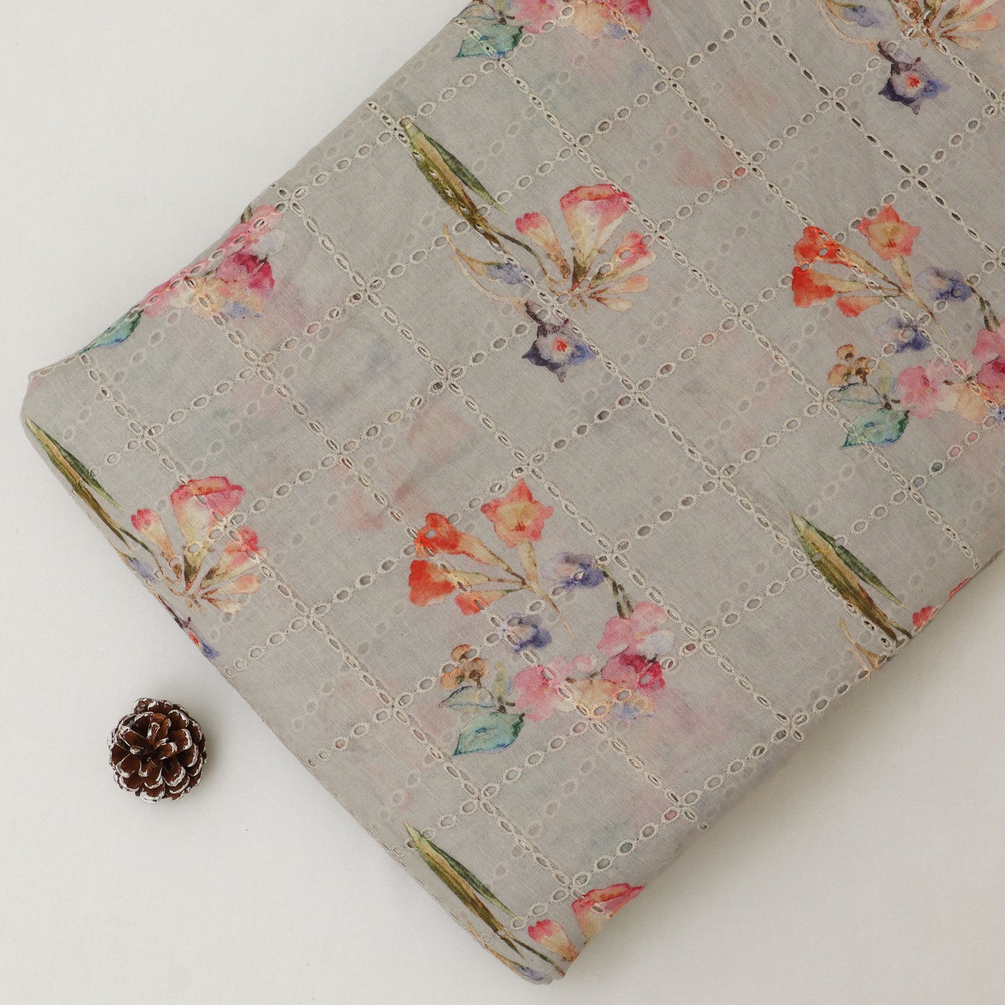 Floral-patterned fabric on a white background with a pine cone