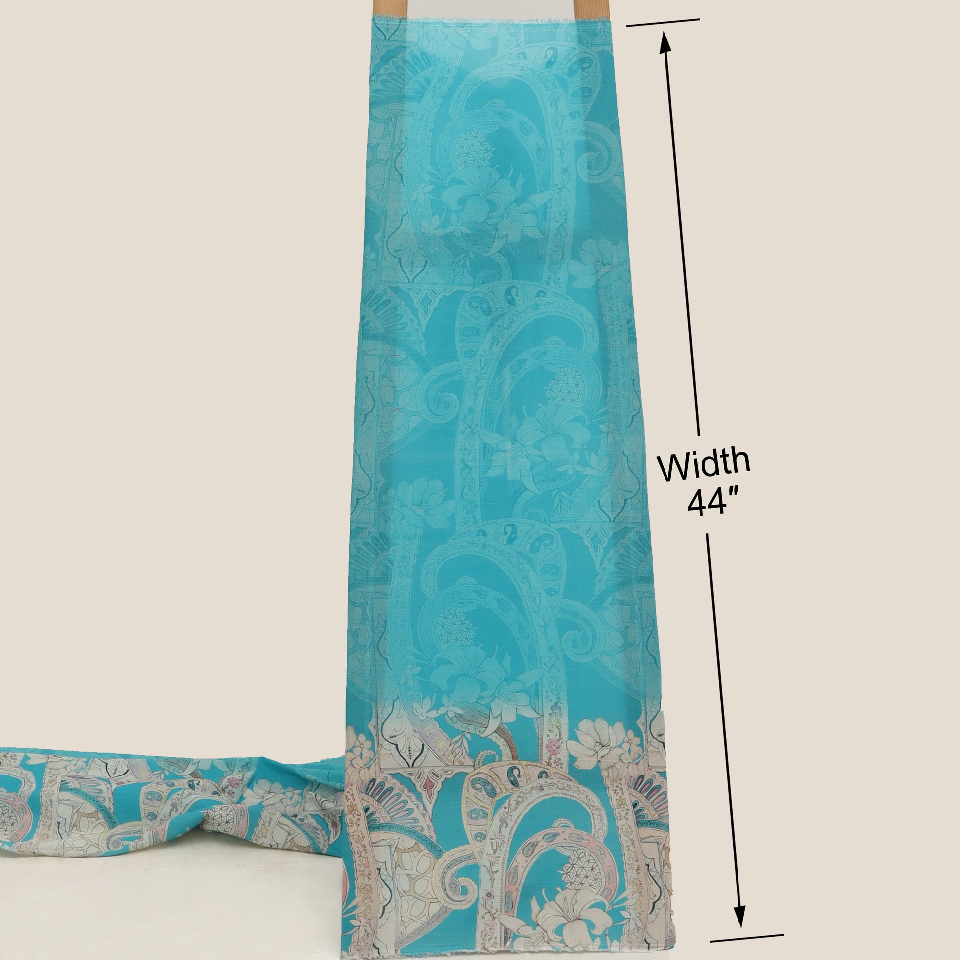 Turquoise fabric with paisley pattern and measurement label on a beige background
