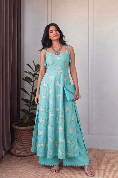 Woman wearing a light blue dress with butterfly patterns indoors.