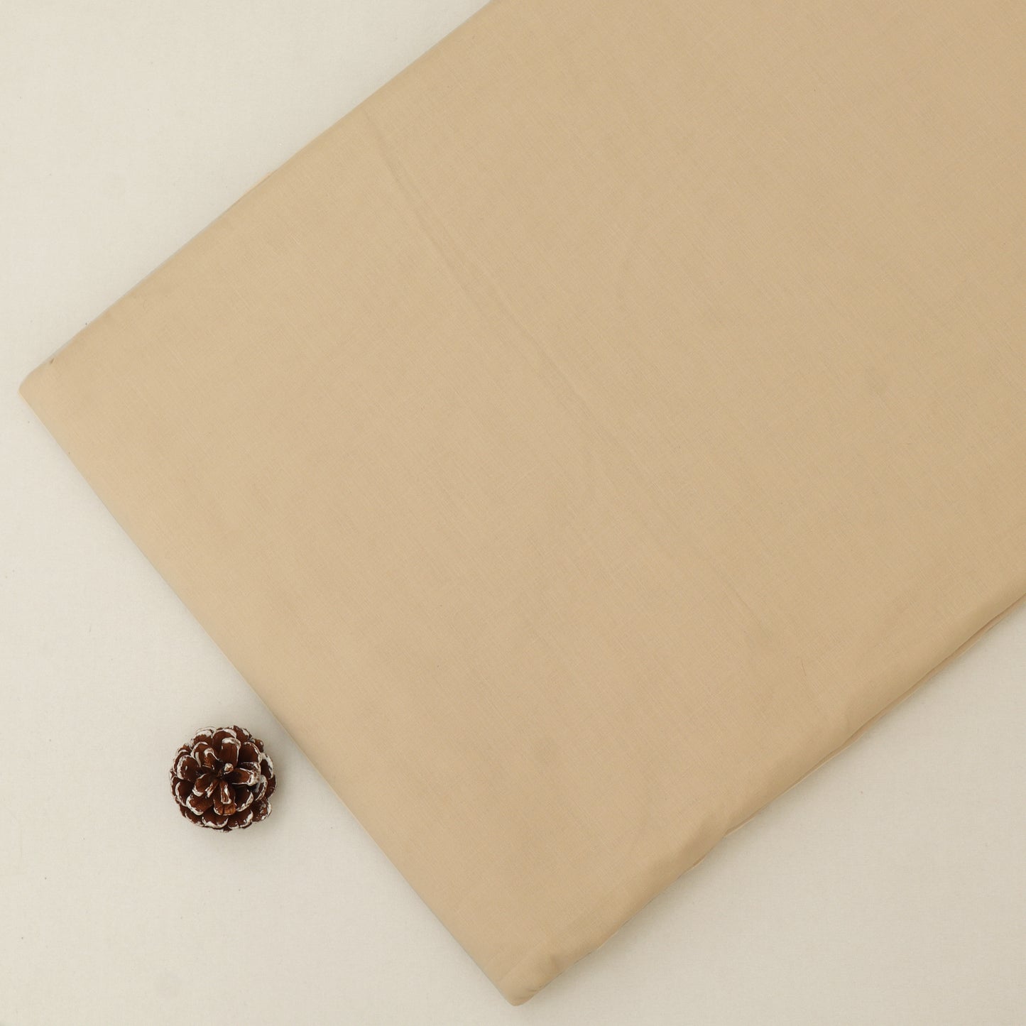 Beige fabric with a pine cone on a light beige background