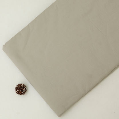 Folded beige fabric with a small pine cone on a light background