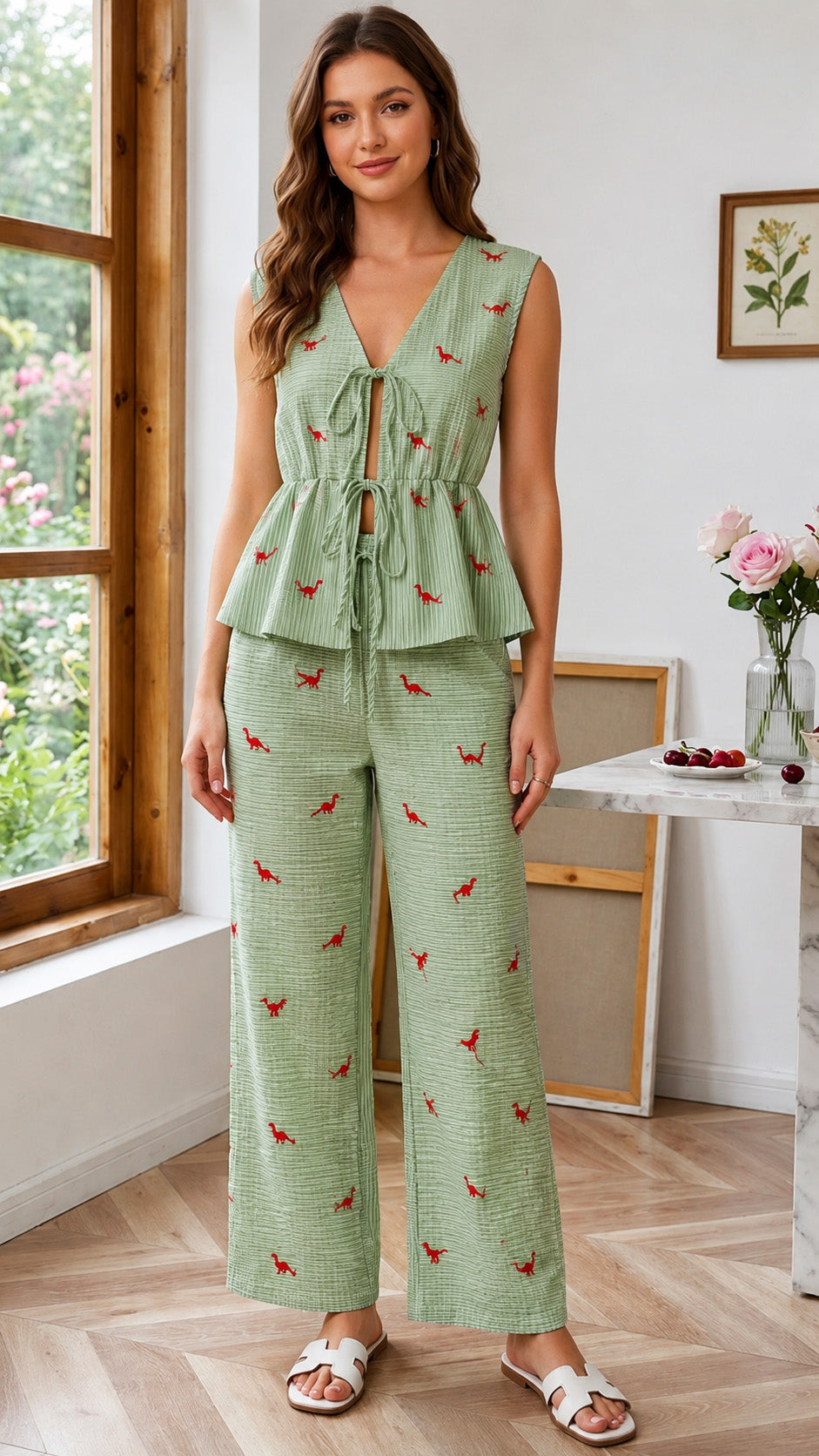 Woman wearing a green patterned jumpsuit standing in a room with a window and table.