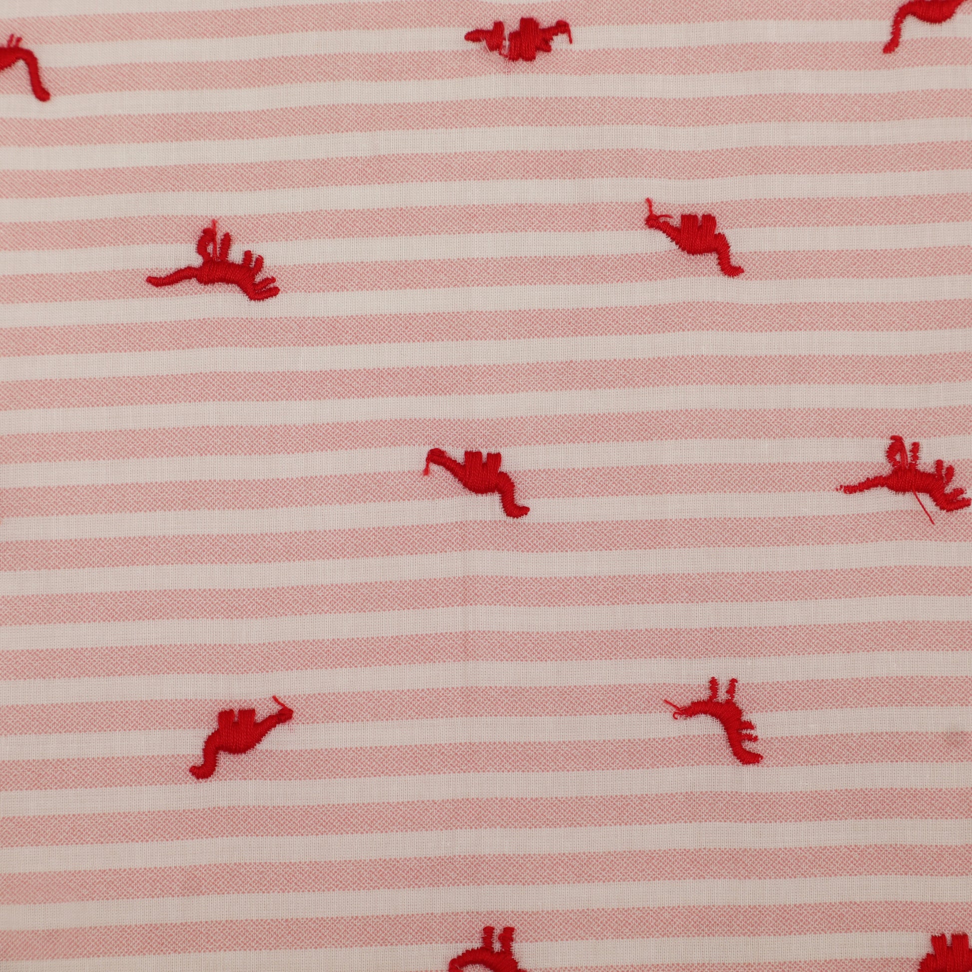 Red embroidered shapes on a pink and white striped fabric