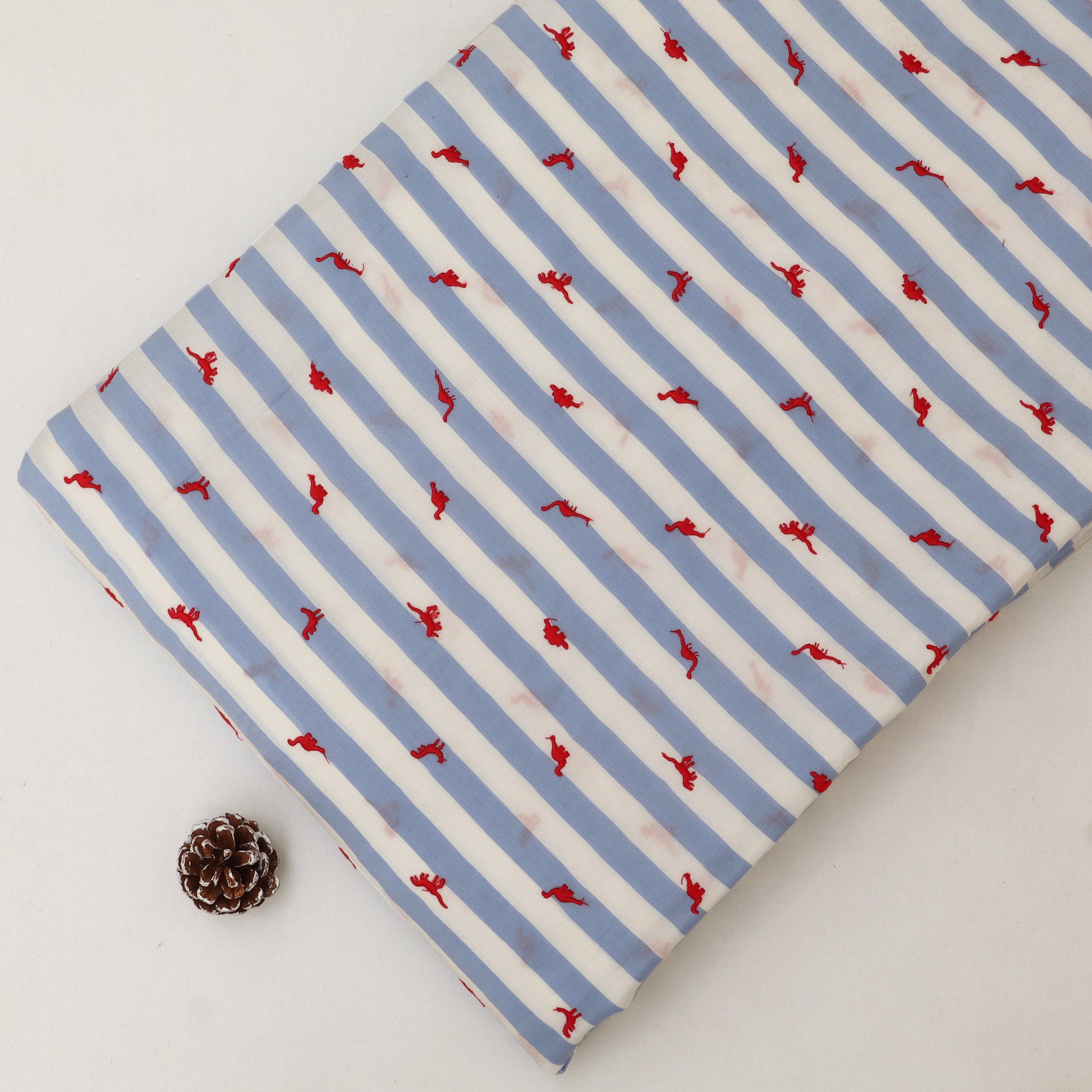 Fabric with blue and white stripes and red patterns on a light gray background