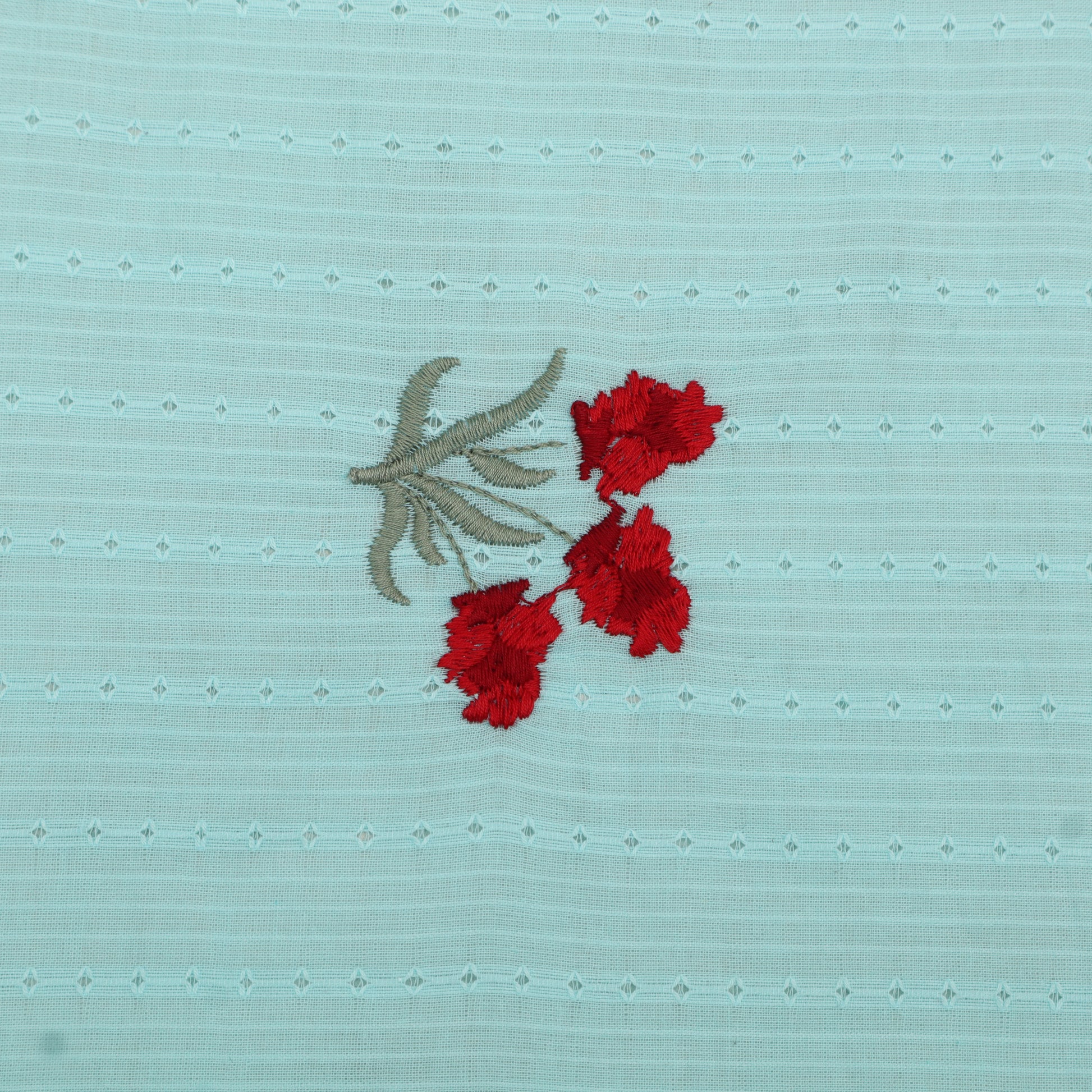 Embroidered red flowers on a light blue fabric background