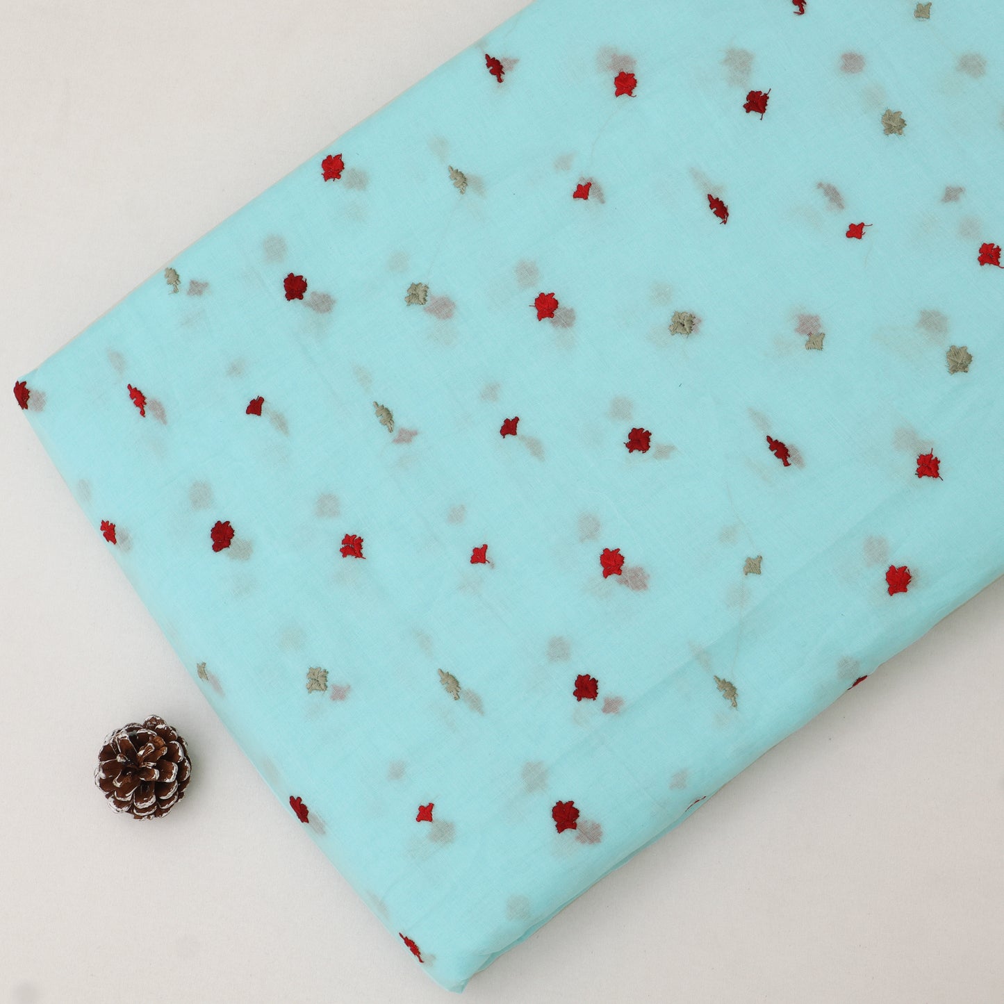 Light blue fabric with red and brown pattern on a white background