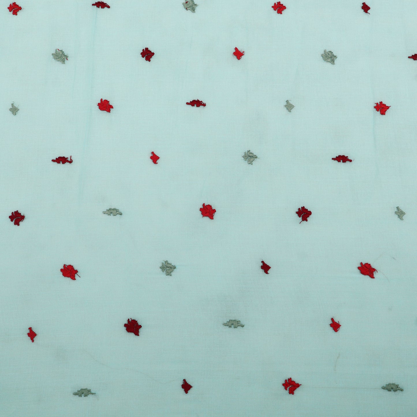 Pattern of red and green leaves on a light blue background