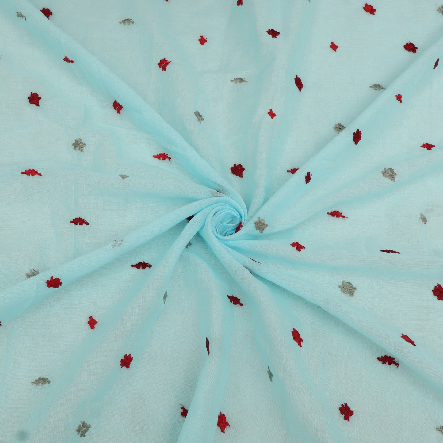 Light blue fabric with small red and gray floral patterns, folded in a swirl.