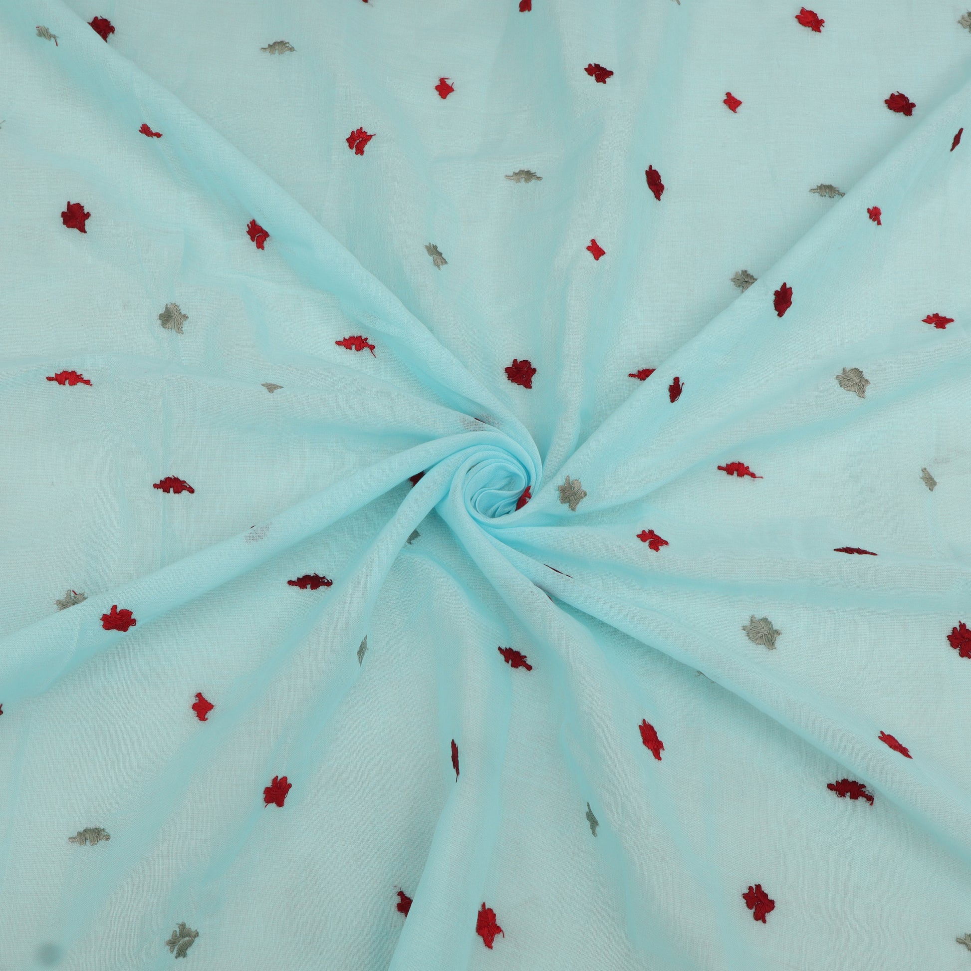 Light blue fabric with small red and gray floral patterns, folded in a swirl.