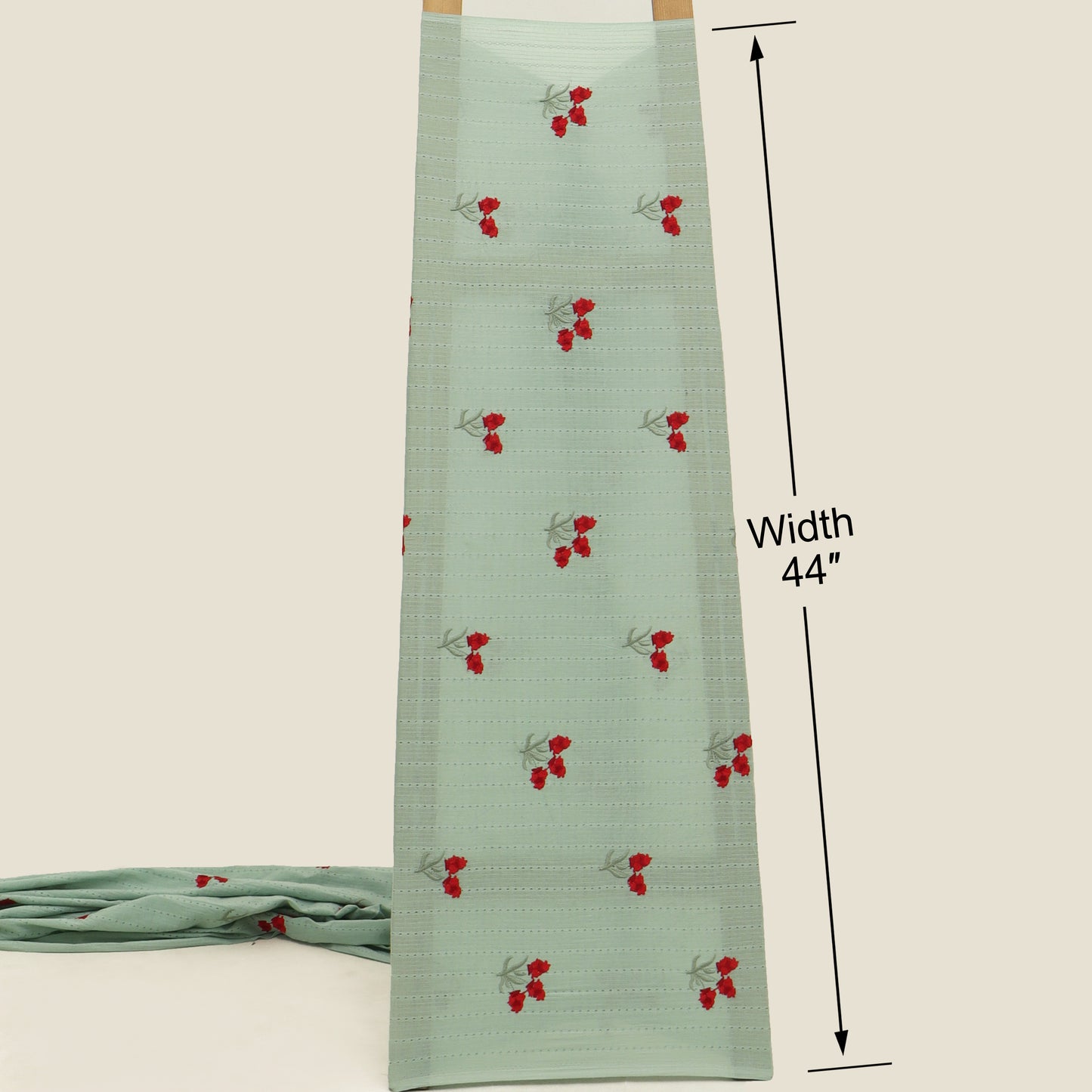 Green fabric with red cherry pattern and measurement label on a beige background
