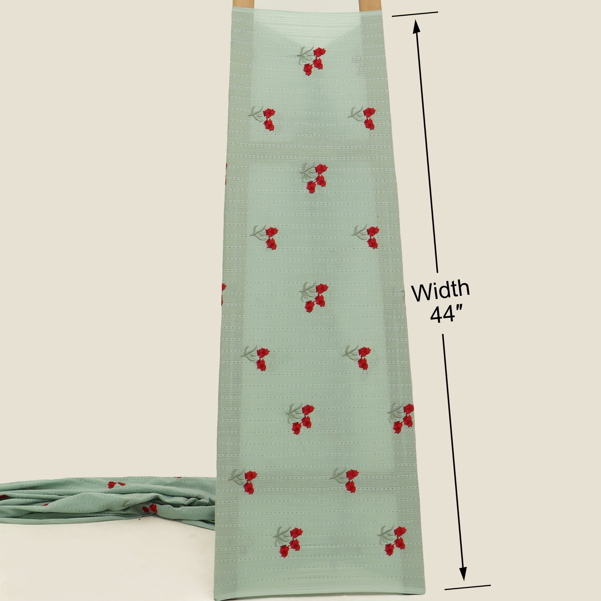 Green fabric with red cherry pattern and measurement label on a beige background