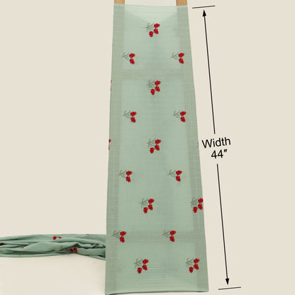 Green fabric with red cherry pattern and measurement label on a beige background